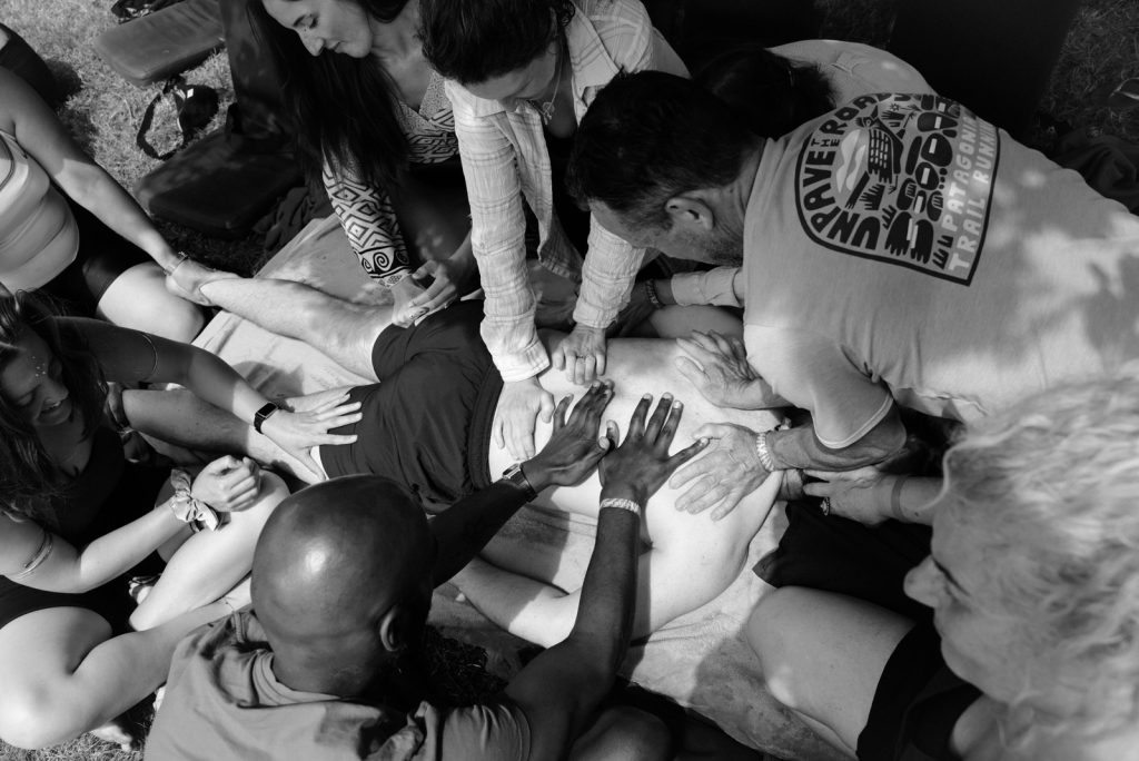 a group of people with their hands on someones back who is lay down